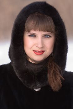 Portrait of the young girl in a black fur coat