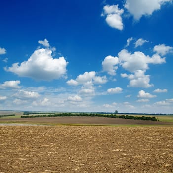 black ploughed field under blue sky