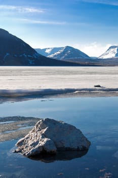 Big gray stone in the lake in mountains