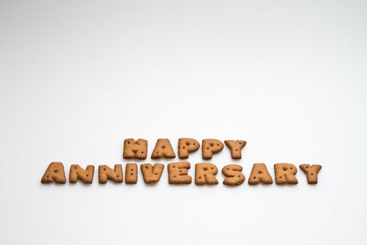 Happy anniversary wording made by brown biscuits on white surface