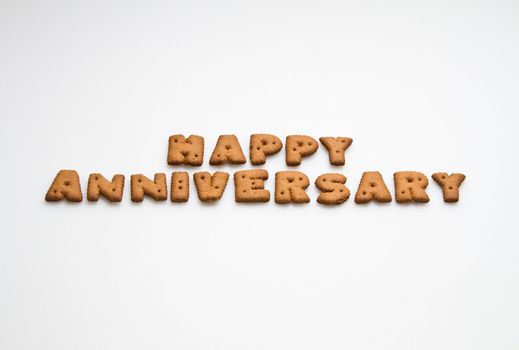 Happy anniversary wording made by brown biscuits on white surface centre position