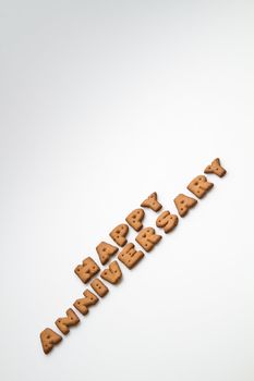 Happy anniversary wording made by brown biscuits slanting on white surface in portrait orientation