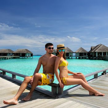 Couple on a tropical beach jetty at Maldives