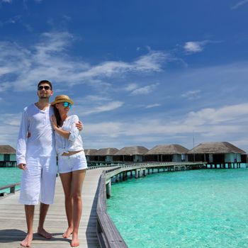 Couple on a tropical beach jetty at Maldives