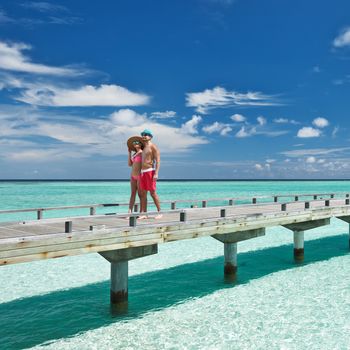 Couple on a tropical beach jetty at Maldives