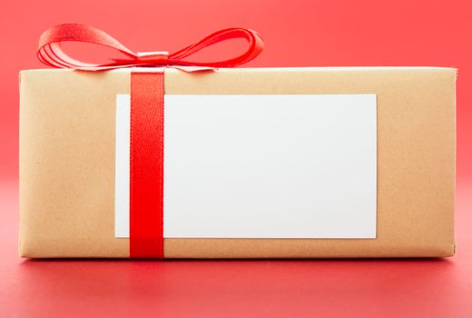 Wrapped gift box with red bow, isolated on red background