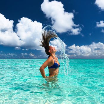 Woman splashing water with her hair in the ocean