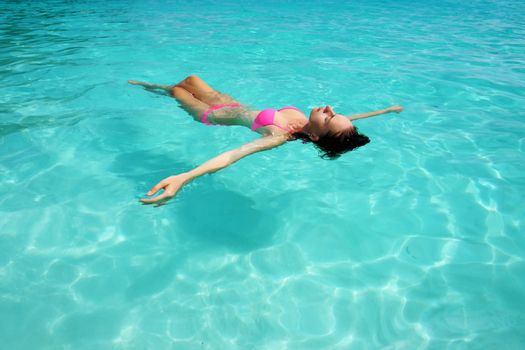 Woman in bikini lying on water at tropical beach