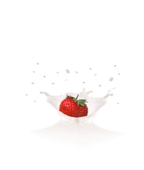 Strawberry falls into milk causing splash and drops