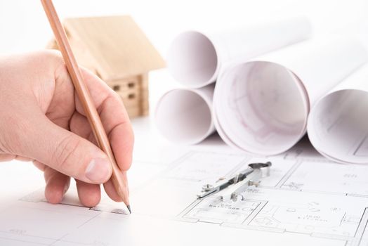 architect hand with pencil drawing blueprints