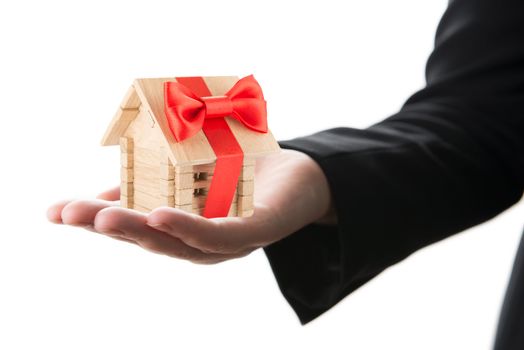 Small wooden house with red bow in a hand