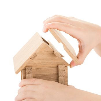 Child hands build a wooden house