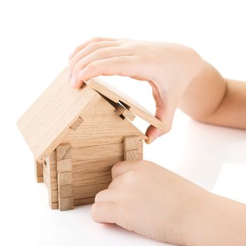 Child hands build a wooden house