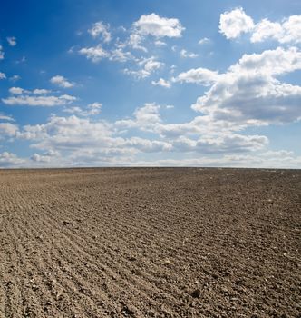 black ploughed field under blue sky