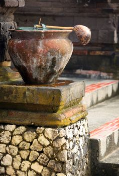 Ancient pot with a ladle before a temple for washing legs. Indonesia. Bali