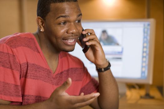 African American young adult talking on cell phone and using computer