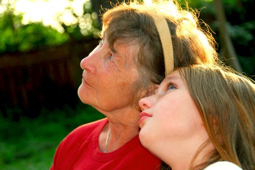 Portrait of grandmother and granddaughter in summer park looking up