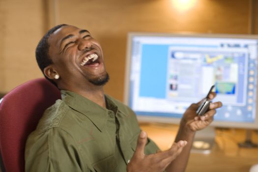 Laughing African American man text messaging on cell phone