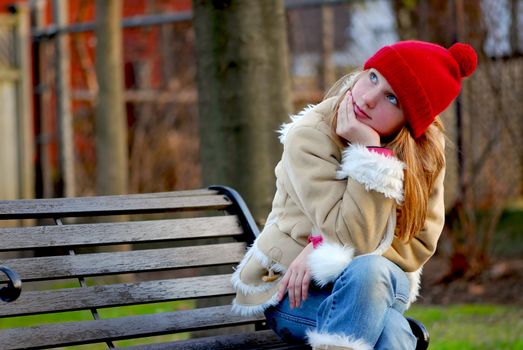 Portrait of a young girl sitting on a bench outside