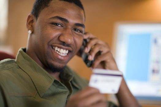 Smiling African American man shopping with credit card and cell phone