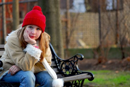 Portrait of a young girl sitting on a bench outside