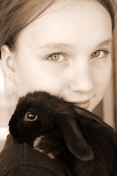 Portrait of a young girl holding a black baby rabbit in sepia