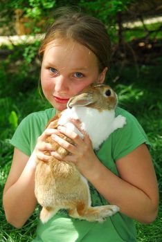 Portrait of a young girl holding a bunny outside