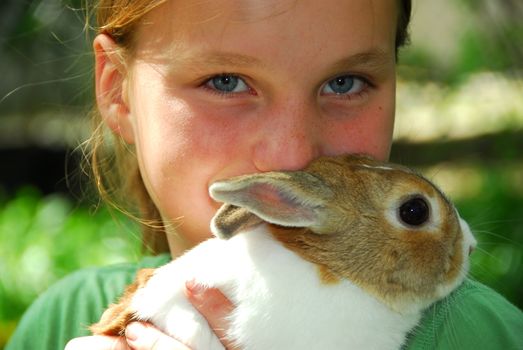 Portrait of a young girl holding a bunny outside