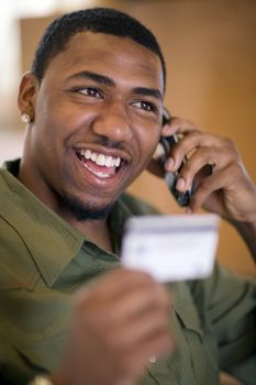 Smiling African American man shopping with credit card and cell phone