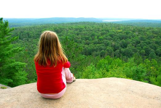 Young girl sitting on an edge of a cliff