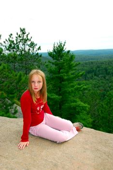 Young girl sitting on an edge of a cliff