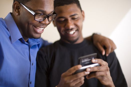 African American young men text messaging on PDA

