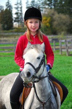 Young girl riding a white pony at countryside