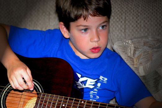 Young boy playing a guitar in a spotlight