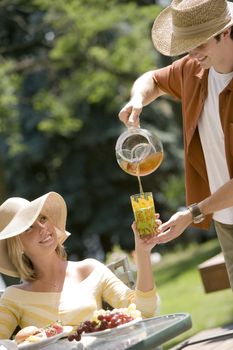 Young man pouring tea for attractive woman at an outdoor picnic lunch