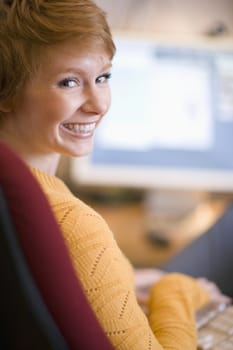 A smiling young woman working at the computer
