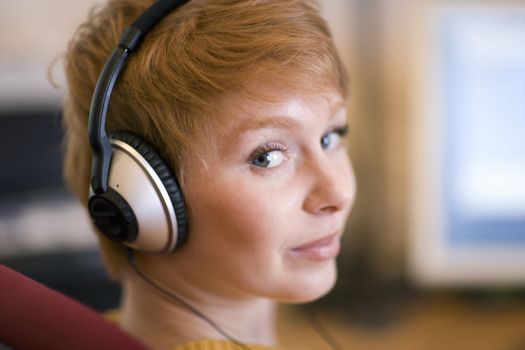 Young woman listening to headphones looking directly at camera