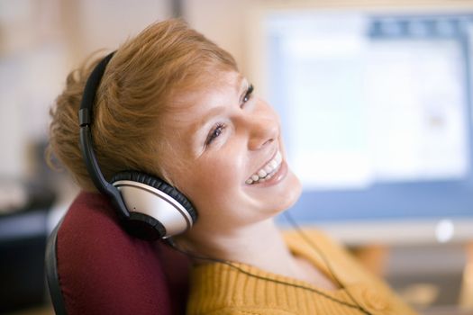 Young laughing woman relaxing in chair listening to headphones