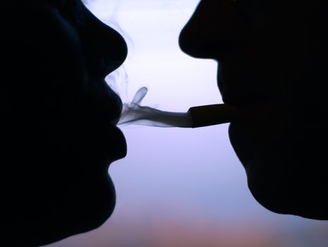 Two silhouettes of smoking people close-up