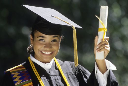 African American woman graduate wearing cap and gown holding up diploma