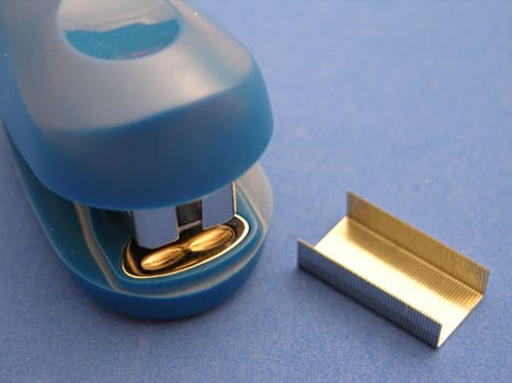 A closeup view of a small stapler on a blue background