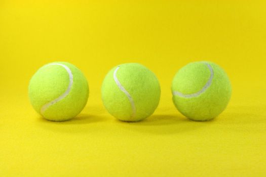 three yellow tennis balls center with yellow background sports concepts