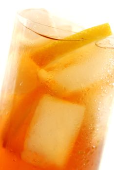 Glass of cold lemon iced tea with ice and lemon, water drops on surface