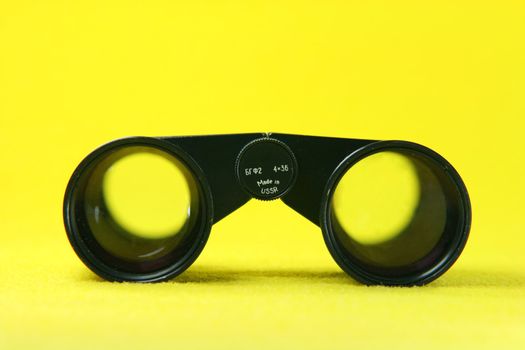 front of black retro binoculars from ussr in yellow background optic tools