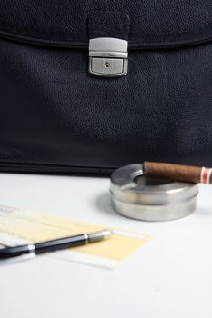focus on the black leather financial deal check writing cigar with black leather briefcase background praspective business concepts