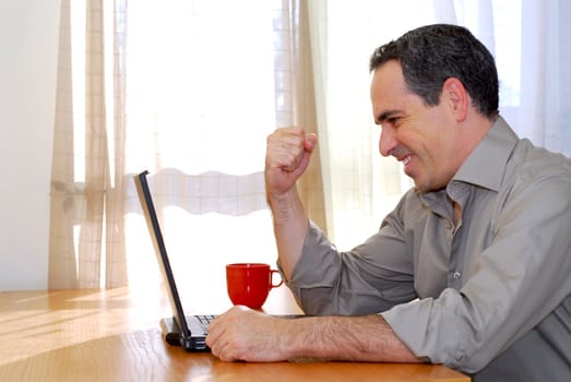 Man sitting at a desk and looking into his computer showing happiness and excitement