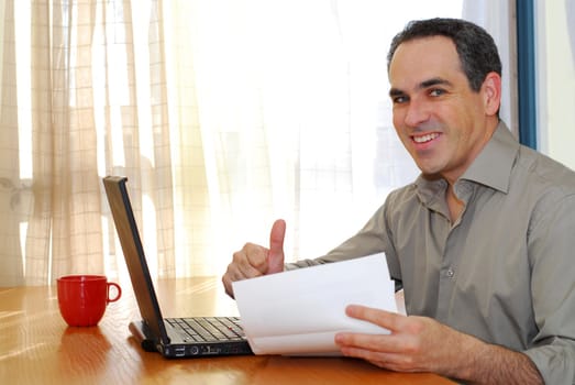 Man sitting at a desk looking at bills and smiling