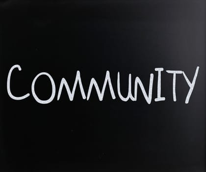 "Community" handwritten with white chalk on a blackboard