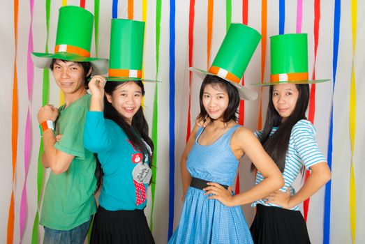 Asian Thai girls and boy hold big green hat on St.Patrick's Day, they act in happiness and celebrating feeling