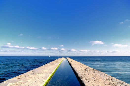 Pier stretching into the sea, with the creek in the middle.
